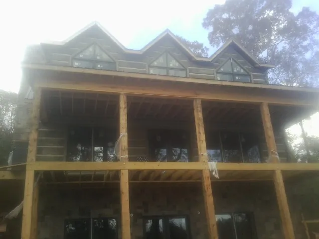 Dormers and porch framing on a large log home under construction — Roof Coating work by our crew in Middlesex